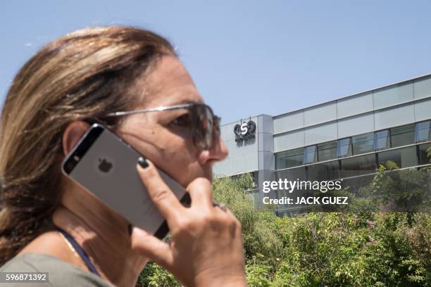 An Israeli woman uses her iPhone in front of the building housing the Israeli NSO group, on August 28 in Herzliya, near Tel Aviv. Apple iPhone...