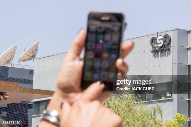 An Israeli woman uses her iPhone in front of the building housing the Israeli NSO group, on August 28 in Herzliya, near Tel Aviv. - Apple iPhone...