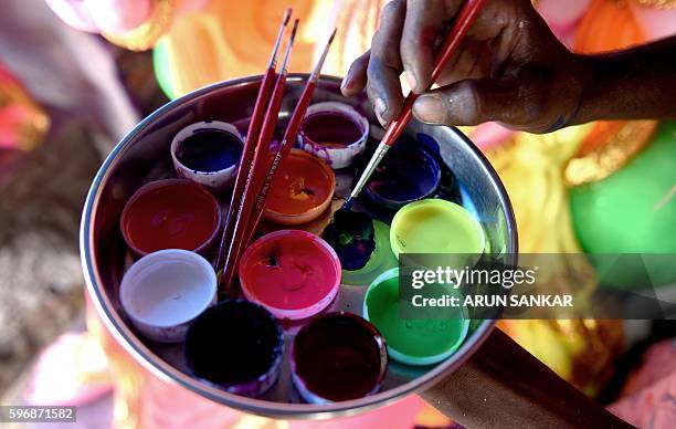 Indian labourer mixes paint as he prepares to give the finishing touches to a statue of the elephant-headed Hindu god Lord Ganesha ahead of the...