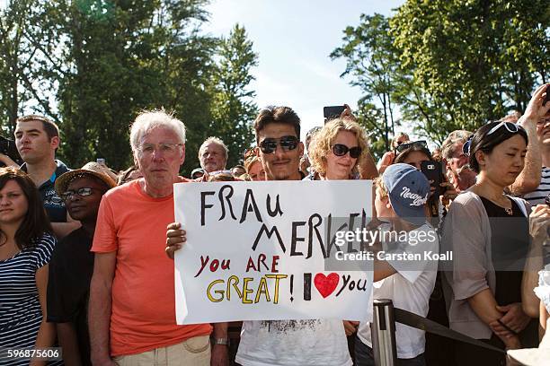 Members of the public who had come for the annual open-house day at the Chancellery follow a talk on the stage with German Chancellor Angela Merkel...