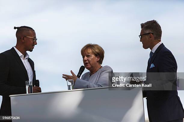 German Chancellor Angela Merkel talks with Jerome Boateng during the annual open-house day at the Chancellery on August 28, 2016 in Berlin, Germany....