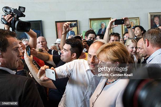 Visitor makes a selfie picture with German Chancellor Angela Merkel during the annual open-house day at the Chancellery on August 28, 2016 in Berlin,...
