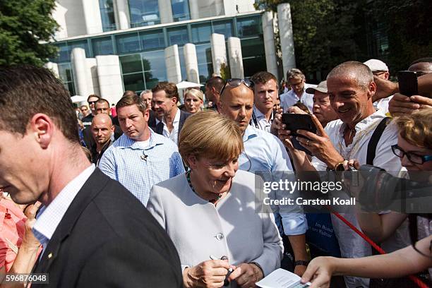 German Chancellor Angela Merkel walks through members of the public who had come for the annual open-house day at the Chancellery on August 28, 2016...