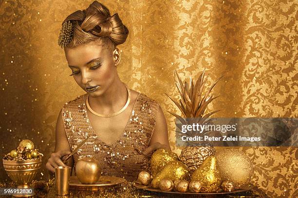 woman with golden body painting having golden dinner - glitter fruit stock pictures, royalty-free photos & images