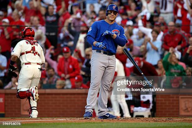 St. Louis Cardinals catcher Yadier Molina runs off the field as Chicago Cubs first baseman Anthony Rizzo tosses his bat after striking out to end the...