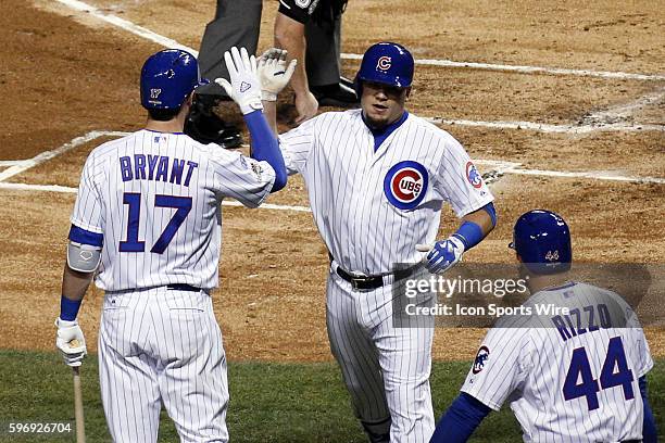 Chicago Cubs left fielder Kyle Schwarber hits a solo home run in the first inning and celebrates with Chicago Cubs third baseman Kris Bryant and...