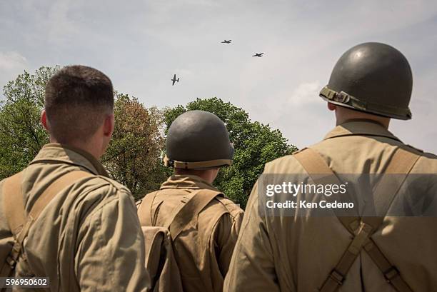 Reenactment soldiers from Ft. Myer watch as vintage WWII planes perform the "missing man formation," during a diverse array of World War II aircraft...