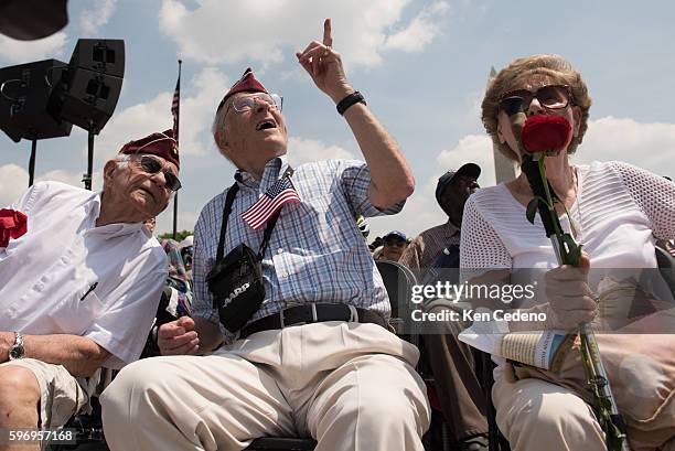 Army Veterans, Harold Radish, left, Eli Linden center, and his wife, right, watch the array of World War II aircraft fly over the National Mall...