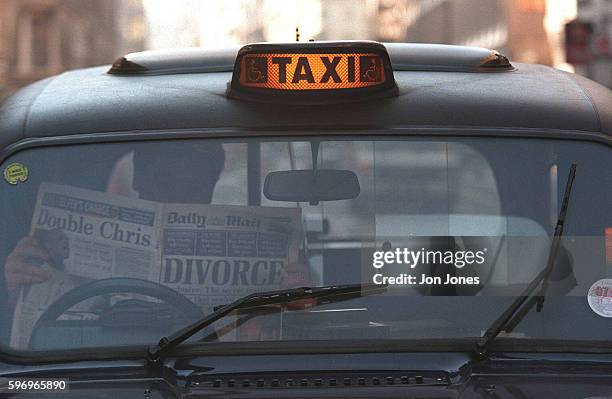 Taxi driver reads the daily Mail newspaper, with its 'DIVORCE' headline, in his cab the day after the announcement of the divorce of Prince Charles,...