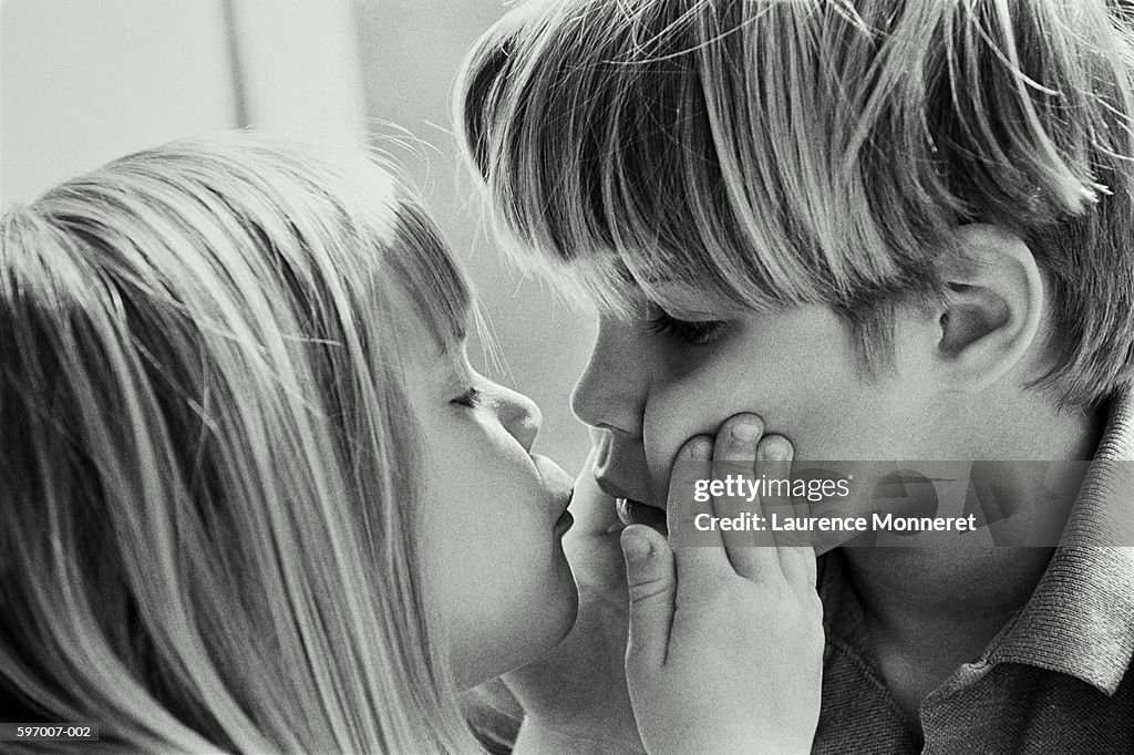 Girl kissing boy (4-6), close-up (B&W)