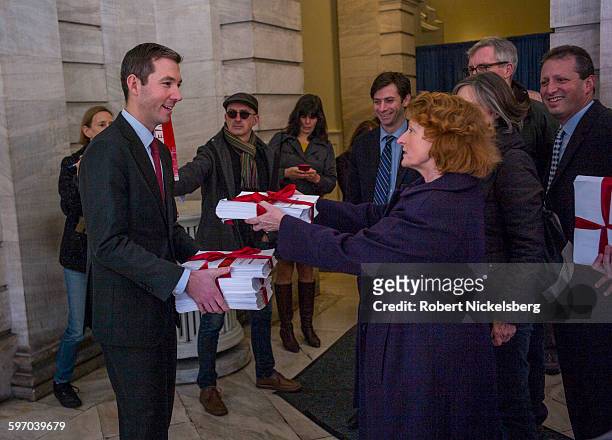 New York State Assemblywoman JoAnne Simon, center right, hands over a stack of signed petitions to Peter Wortheim, left, a senior aide to the Deputy...
