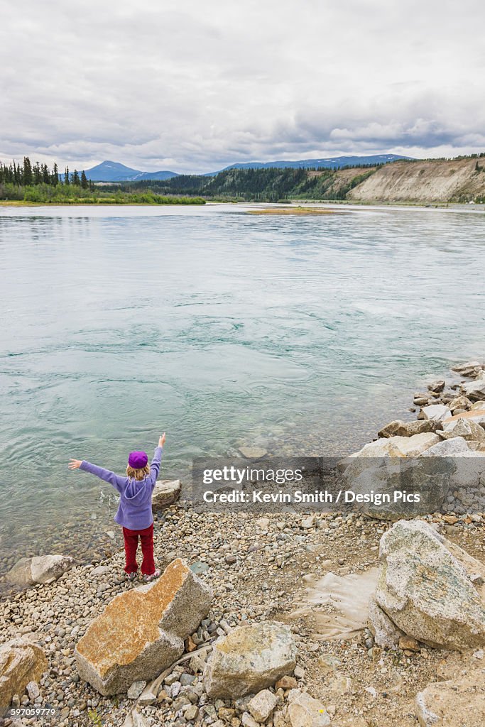 Young girl playing along the bank of the Yukon River, Whitehorse, Yukon Territory, Canada, Summer