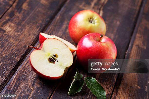 whole and sliced red apples on dark wood - gala apples stock pictures, royalty-free photos & images