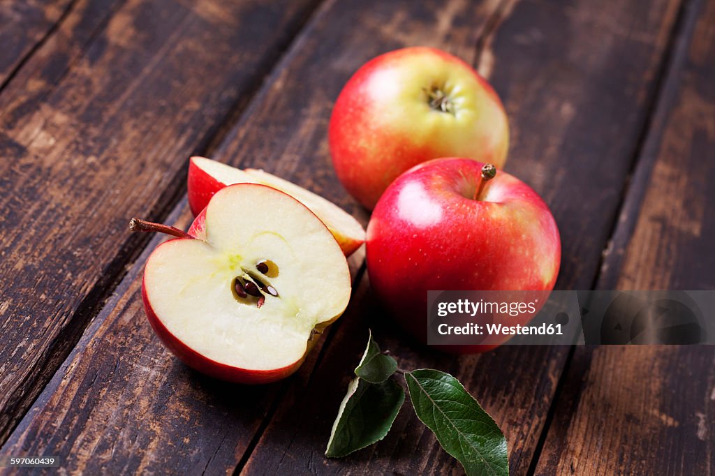 Whole and sliced red apples on dark wood