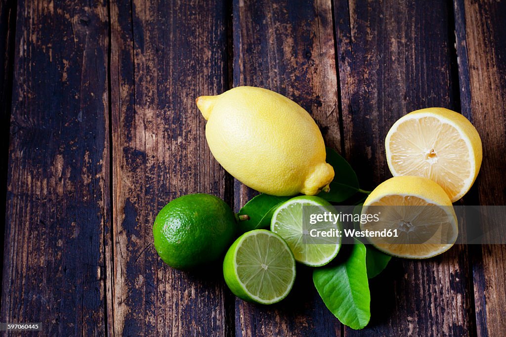 Whole and sliced lemons and limes on dark wood