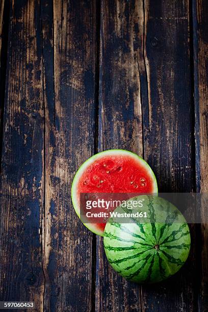 sliced mini watermelon on dark wood - melone stock-fotos und bilder