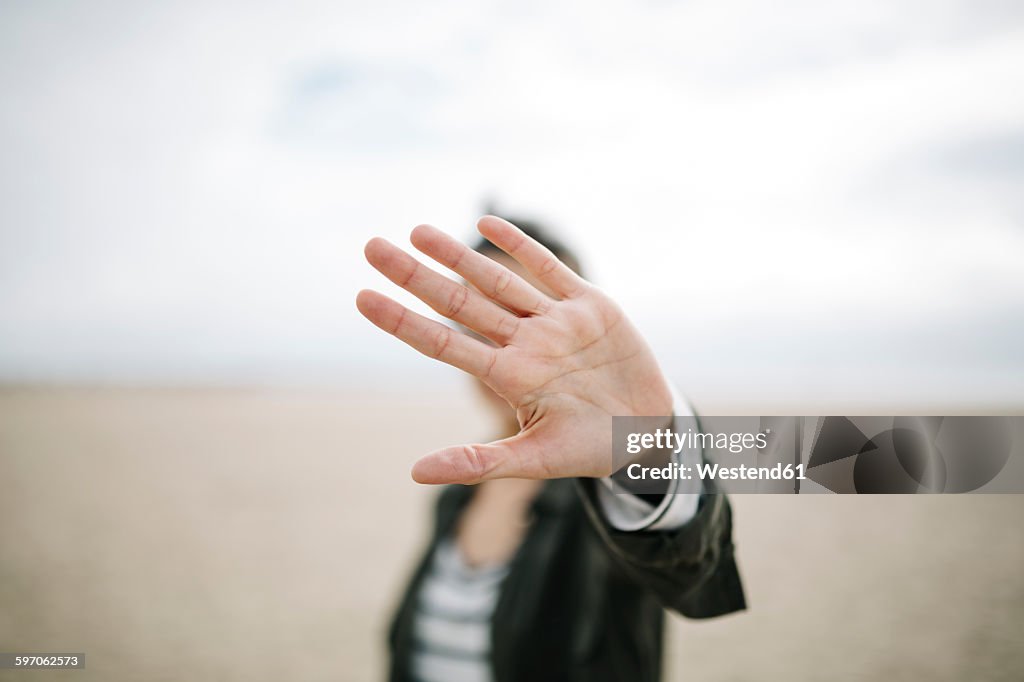 Young woman hiding face behind her outstretched hand