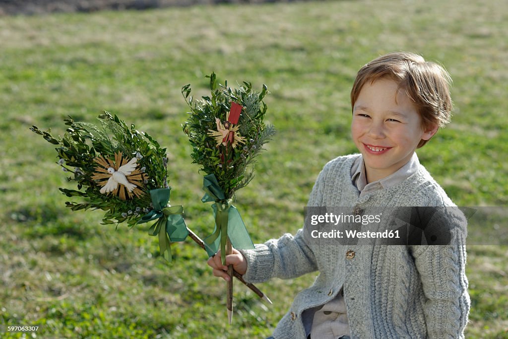Germany, Upper Bavaria, Portrait of smiling little boy with Palmbusch on a meadow