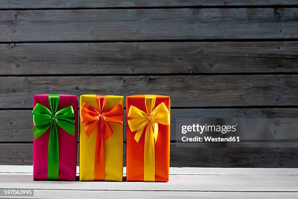 three gift packages in front of wooden wall - sala di lusso foto e immagini stock