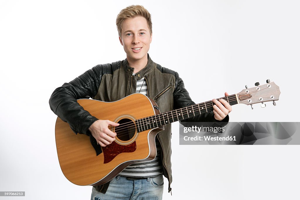 Smiling young man playing guitar