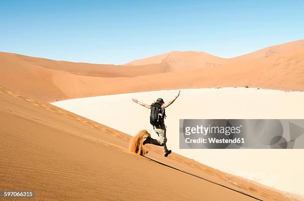 namibia, namib desert, woman running down a dune on the way to deadvlei - sossusvlei stock pictures, royalty-free photos & images