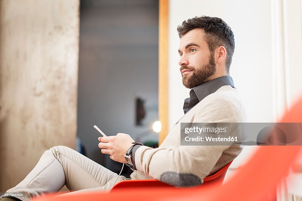Man sitting in chair holding cell phone