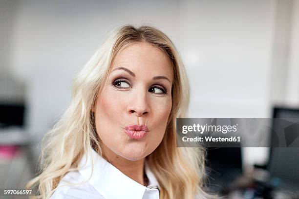 blond woman in office pouting mouth - puckering - fotografias e filmes do acervo