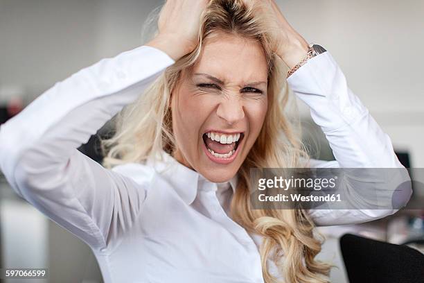 blond woman in office tearing her hair out - tearing your hair out photos et images de collection