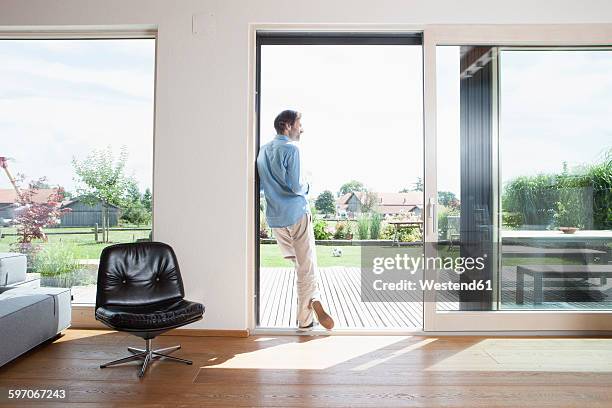 mature man leaning in garden door, rear view - glass door stock pictures, royalty-free photos & images