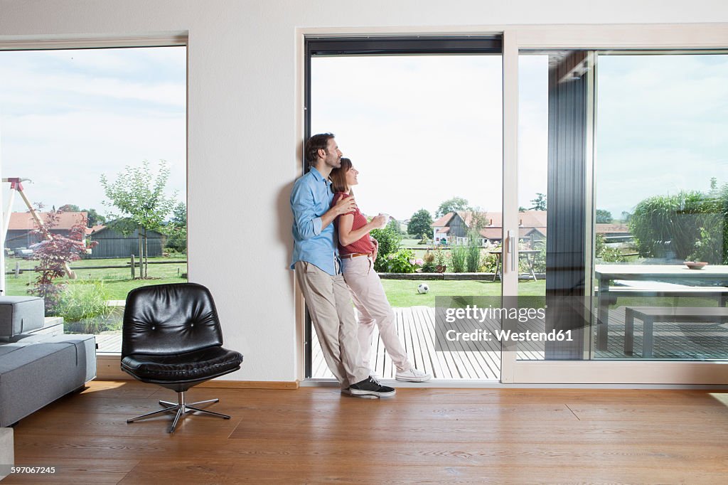 Mature couple leaning in garden door with cup of coffee