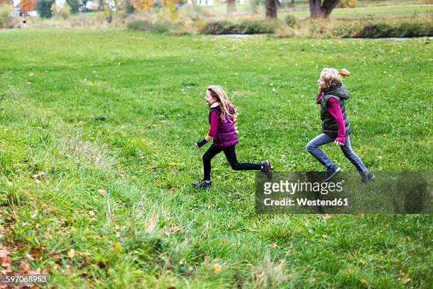 boy and girl running over a meadow - acchiappino foto e immagini stock