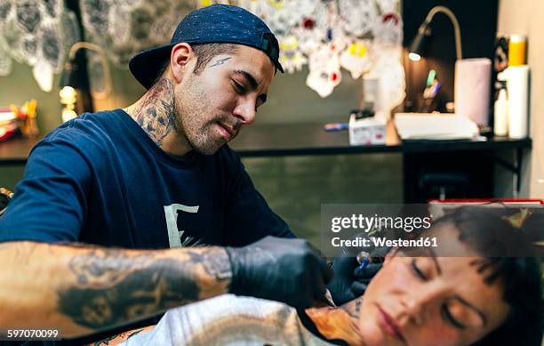 woman receiving tattoo in tattoo studio - tattooing stock pictures, royalty-free photos & images