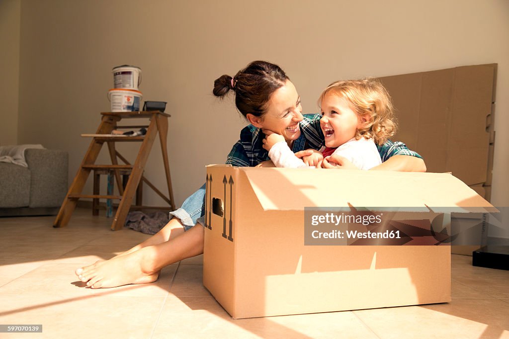 Laughing woman with daughter sitting in cardboard box