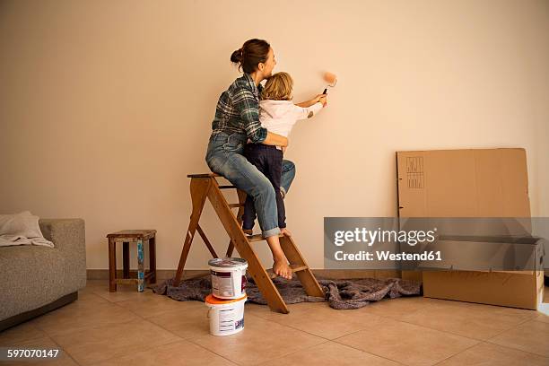 mother and daughter painting a wall - holding paint roller stock pictures, royalty-free photos & images