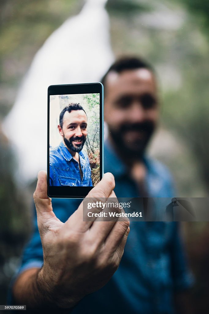 Bearded man showing selfie on display of his smartphone