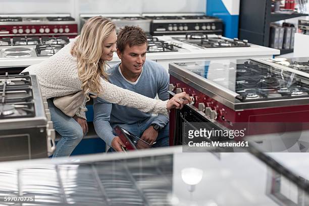 young couple testing gas stove in shop - appliance shopping stock pictures, royalty-free photos & images
