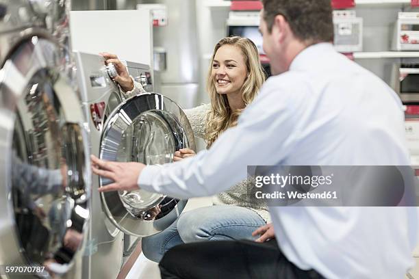 shop assistant explaining washing machine to customer - buying washing machine stockfoto's en -beelden