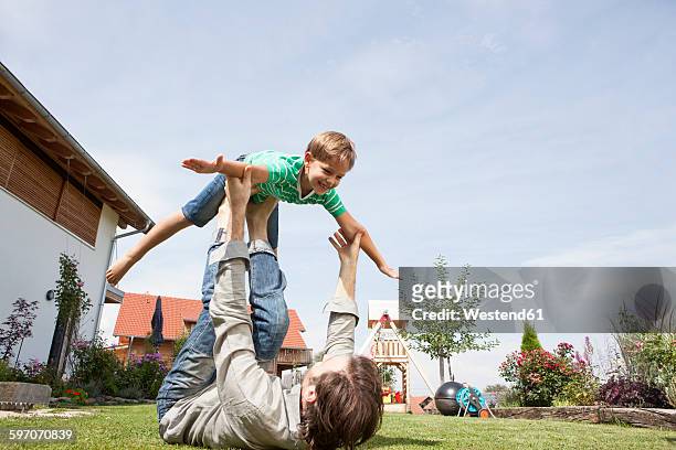 playful father with son in garden - hacer el avión fotografías e imágenes de stock
