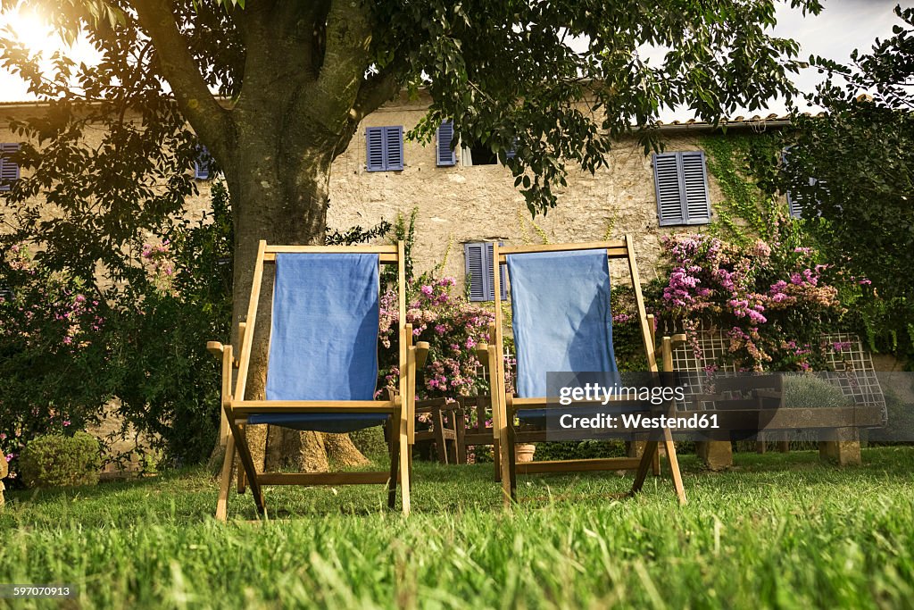 Italy, Tuscany, Maremma, Deck chairs in flowering garden of a country house