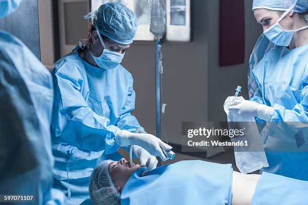 surgical team preparing patient for operation - operating gown stock pictures, royalty-free photos & images