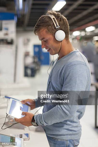 young woman with headphones testing digital tablet in a shop - headphones in store stock pictures, royalty-free photos & images