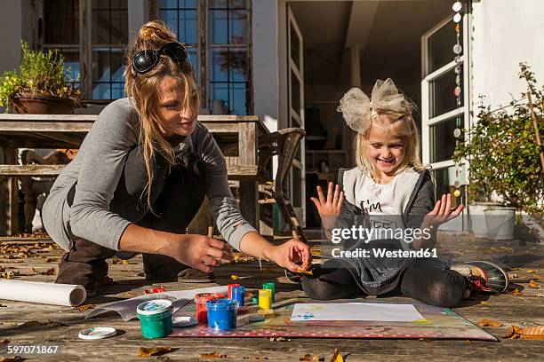 mother and her little daughter painting with finger colours on the terrace - 4 girls finger painting foto e immagini stock