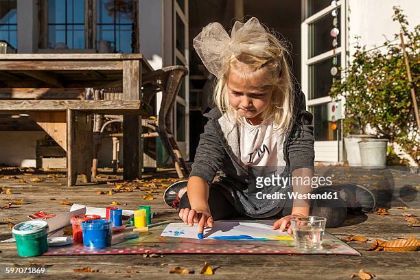 blond little girl painting with finger colours on the terrace - 4 girls finger painting 個照片及圖片檔
