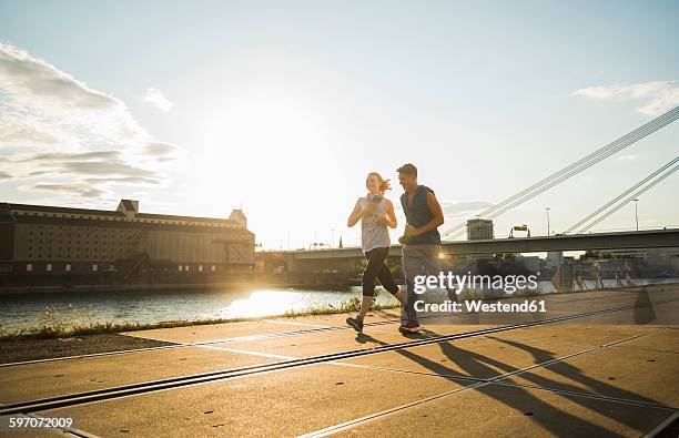 young couple running by the riverside - mannheim stock-fotos und bilder