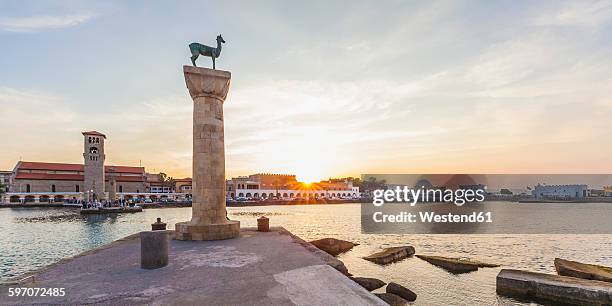 greece, rhodes, entrance to mandraki harbour at sunset - pueblo de rodas fotografías e imágenes de stock