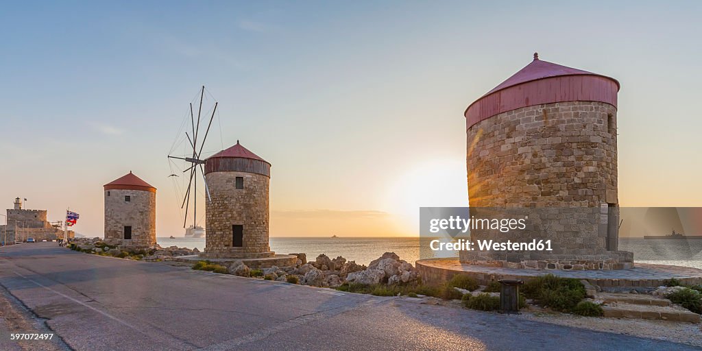 Greece, Rhodes, mole of Mandraki harbour with windmills at sunset