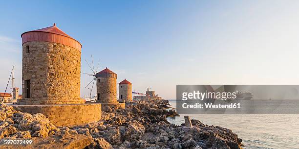 greece, rhodes, mole of mandraki harbour with windmills and cruise ship in background - pueblo de rodas fotografías e imágenes de stock