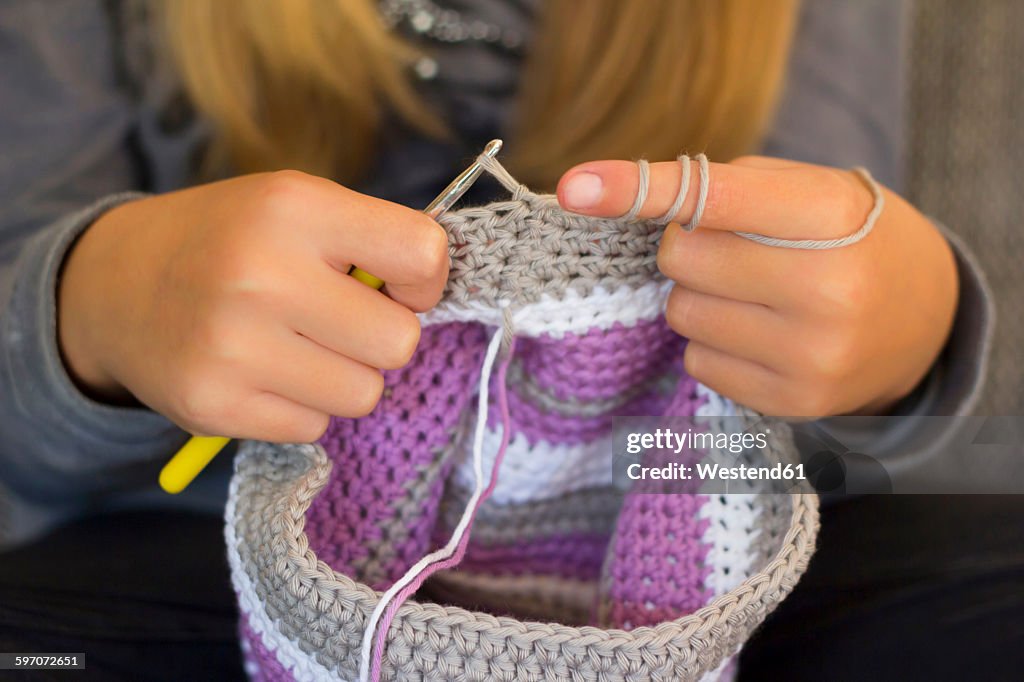 Girl crocheting a cap, close-up