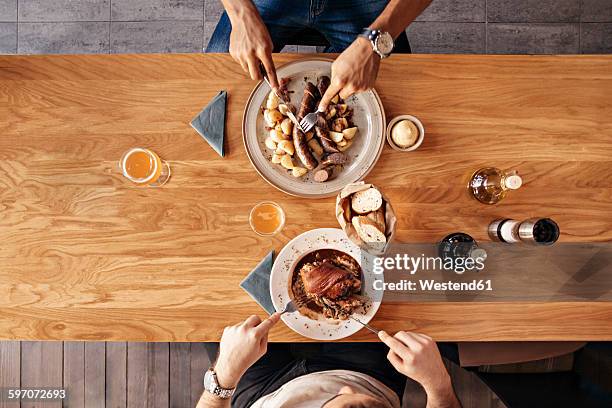 two men in restaurant having lunch - bierwurst stock-fotos und bilder