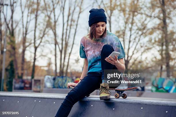 young woman at skatepark looking at cell phone - skate half pipe stock pictures, royalty-free photos & images